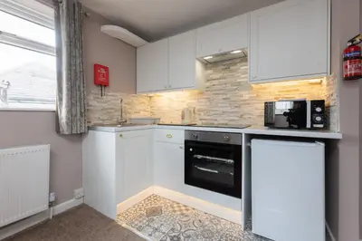 a kitchen with white cabinets and a black dishwasher at Beachcliffe Holiday Apartments in Blackpool