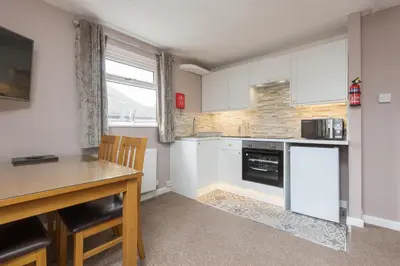 a kitchen with white cabinets and a wooden table at Beachcliffe Holiday Apartments in Blackpool