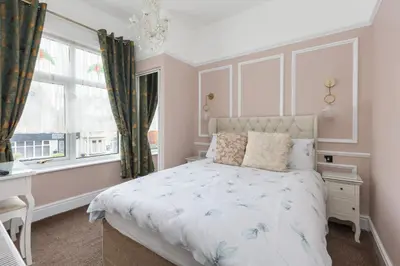 a bedroom with a bed and a desk and a window at Beachcliffe Holiday Apartments in Blackpool