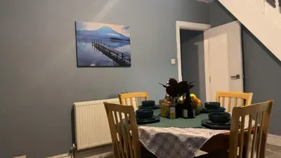 a dining room with a table with chairs and a painting at true and fruitful vine by Everton and Liverpool footy club in Liverpool