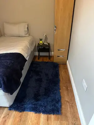 a bedroom with a bed and a blue rug at true and fruitful vine by Everton and Liverpool footy club in Liverpool