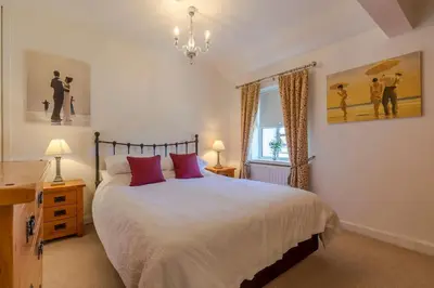 a bedroom with a large bed with red pillows at Shrimpers Cottage in Lytham St Annes