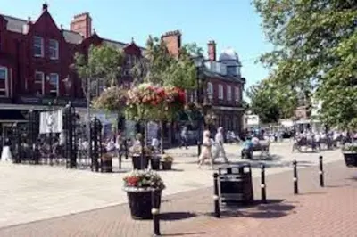 a city street with people walking and a fence at Shrimpers Cottage in Lytham St Annes