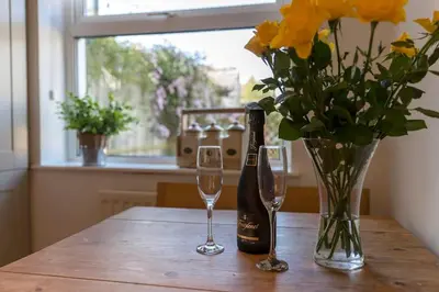a table with a bottle of wine and two glasses at Shrimpers Cottage in Lytham St Annes