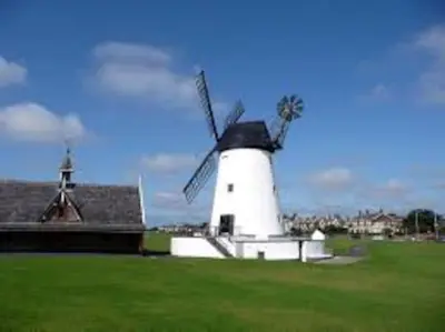 a windmill sitting in a field next to a house at Shrimpers Cottage in Lytham St Annes