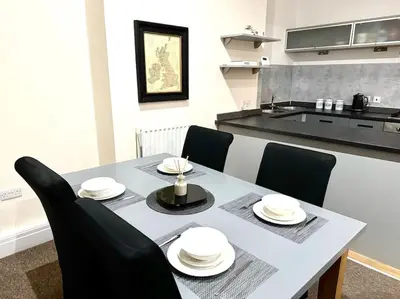 a dining room table with black chairs and a kitchen at City Centre 2 Bed 2 Bath Apartment in Preston