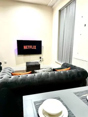 a living room with a black couch and a television at Luxury City Apartment 2 Bedroom Suite in Preston