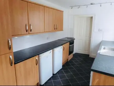 a kitchen with wooden cabinets and a black counter top at Ormskirk lets in Ormskirk