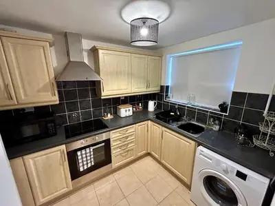 a kitchen with wooden cabinets and a washer and dryer at 3 Double Bedrooms, Lancashire Townhouse, a base to explore in Upholland