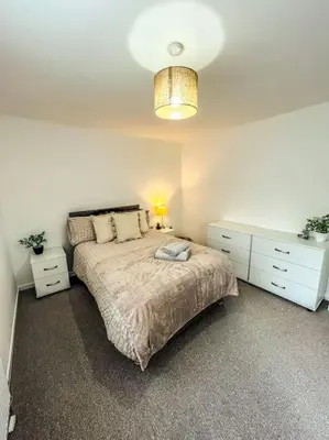 a bedroom with a bed and two dressers and a lamp at 3 Double Bedrooms, Lancashire Townhouse, a base to explore in Upholland