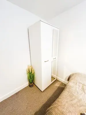 a white cabinet in a bedroom with a potted plant at 3 Double Bedrooms, Lancashire Townhouse, a base to explore in Upholland