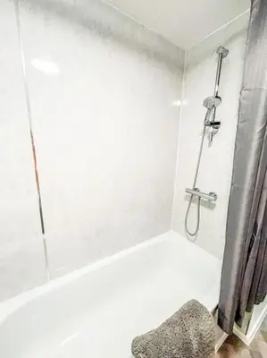 a white bathroom with a shower with a chair at 3 Double Bedrooms, Lancashire Townhouse, a base to explore in Upholland