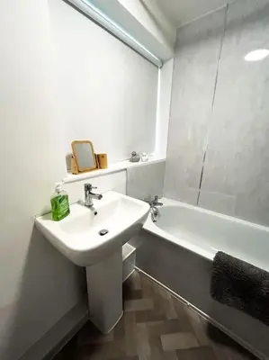 a white bathroom with a sink and a bath tub at 3 Double Bedrooms, Lancashire Townhouse, a base to explore in Upholland