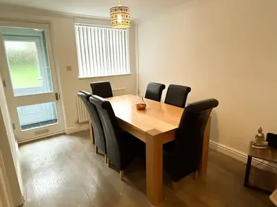 a dining room table with black chairs around it at 3 Double Bedrooms, Lancashire Townhouse, a base to explore in Upholland