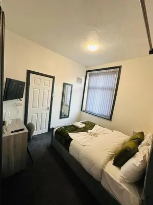 a bedroom with a bed and a desk and a window at The New Valeron Hotel in Blackpool