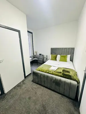 a bedroom with a large bed in a white room at The New Valeron Hotel in Blackpool