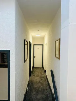 a hallway with a white door and pictures on the walls at The New Valeron Hotel in Blackpool