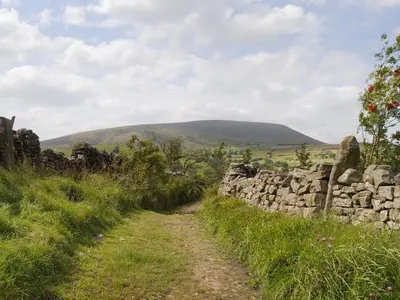 a stone wall next to a dirt road at The Stable - 30562 in Whalley