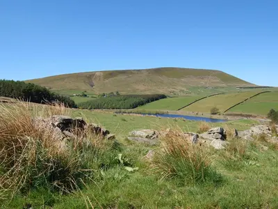 a grassy hill with a river in a field at The Stable - 30562 in Whalley