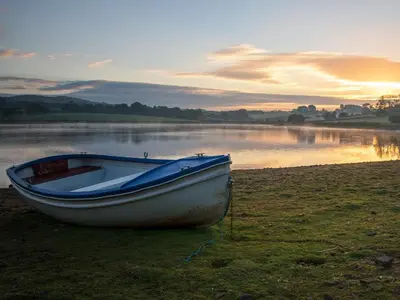a boat sitting on the shore of a lake at The Stable - 30562 in Whalley