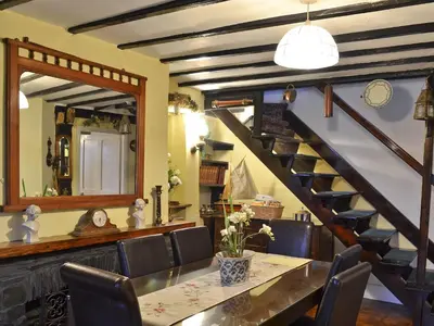 a dining room with a table and a staircase at Tom's Cottage in Dalton in Furness