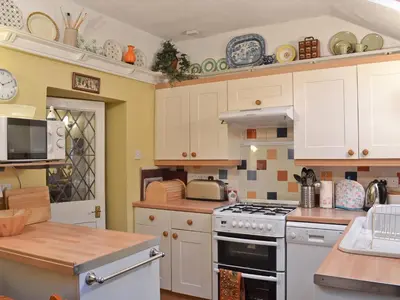 a kitchen with white cabinets and a stove top oven at Tom's Cottage in Dalton in Furness