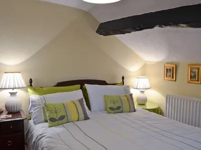 a bedroom with a bed with green and white pillows at Tom's Cottage in Dalton in Furness