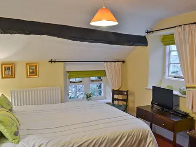 a bedroom with a bed and a tv and windows at Tom's Cottage in Dalton in Furness