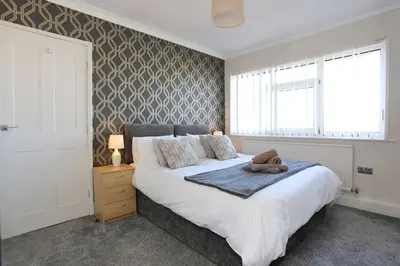 a bedroom with a large white bed and a window at Fabulous beachfront 3 bed house with parking in Cleveleys