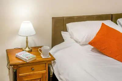 a bed with an orange pillow and a table with a lamp at 2 Bed in Oakenclough oc-m30216 in Scorton