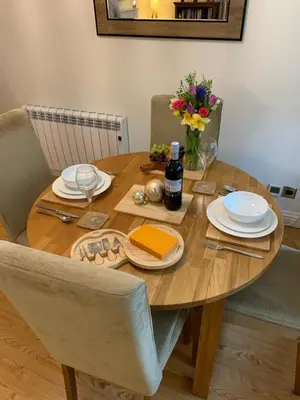 a wooden table with plates and wine glasses and flowers at Willow View, Cartmel in Cartmel