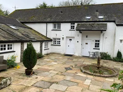 a white house with a patio and a courtyard at Willow View, Cartmel in Cartmel