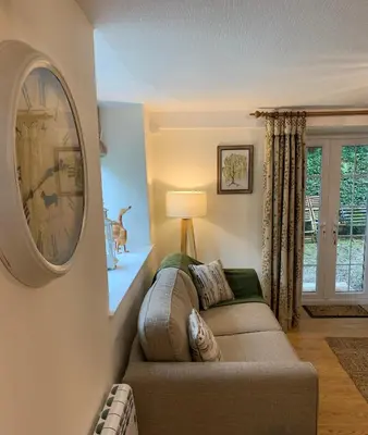 a living room with a couch and a clock on the wall at Willow View, Cartmel in Cartmel