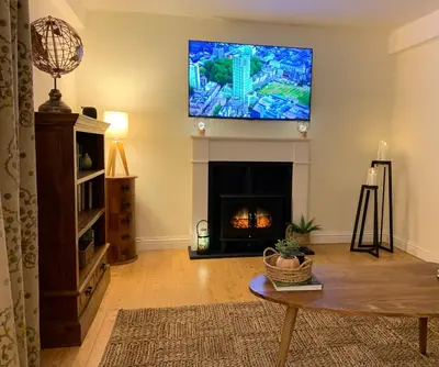 a living room with a fireplace and a flat screen tv at Willow View, Cartmel in Cartmel
