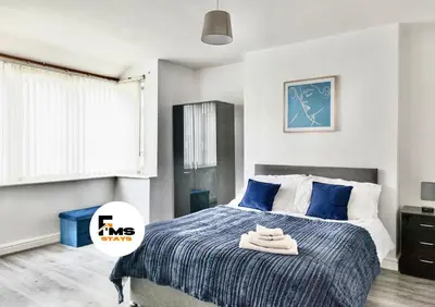 a bedroom with a bed with blue sheets and blue pillows at Large 6 Bed House, Long Term Stay Savings, Contractors, Professionals, Big Groups, Free Parking! in Liverpool