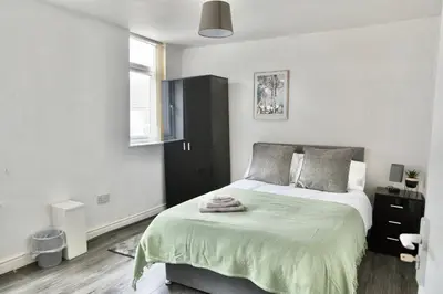 a bedroom with a bed with a green blanket on it at Large 6 Bed House, Long Term Stay Savings, Contractors, Professionals, Big Groups, Free Parking! in Liverpool
