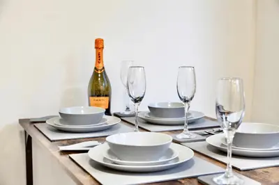 a table with plates and glasses and a bottle of wine at Large 6 Bed House, Long Term Stay Savings, Contractors, Professionals, Big Groups, Free Parking! in Liverpool