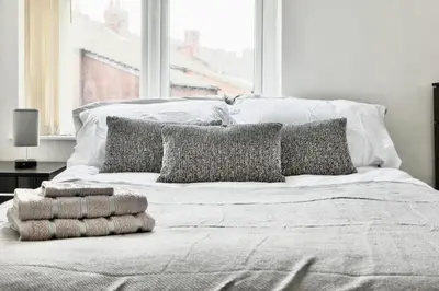 a white bed with pillows on it in a bedroom at Large 6 Bed House, Long Term Stay Savings, Contractors, Professionals, Big Groups, Free Parking! in Liverpool
