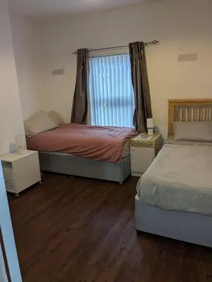 two beds in a room with wooden floors and a window at Best homestay Close To City Centre in Liverpool