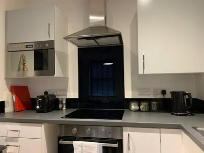 a kitchen with white cabinets and a stove top oven at Bright 1 bed Apartment with Parking in Preston