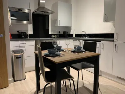 a kitchen with a table and chairs with wine glasses at Bright 1 bed Apartment with Parking in Preston