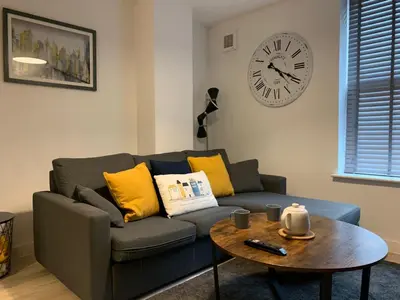 a living room with a couch and a clock on the wall at Bright 1 bed Apartment with Parking in Preston