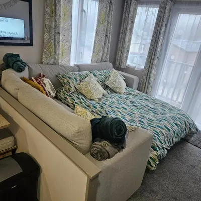 a bed in a room with a couch and windows at Escape in Carnforth Lodge - Sleeps 6 in Carnforth