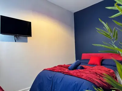 a bedroom with a bed with a red blanket and a flat screen tv at TV Every Bedroom 4 Bed 2 Bath Free Parking in Liverpool
