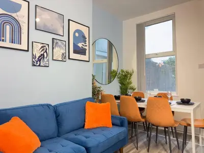a living room with a blue couch and orange pillows at TV Every Bedroom 4 Bed 2 Bath Free Parking in Liverpool