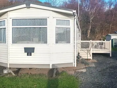 a white tiny house with a porch and a deck at Cookies Corner in Millom
