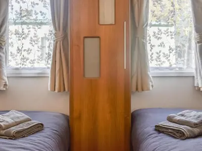a bedroom with a wooden door and two beds at Cookies Corner in Millom