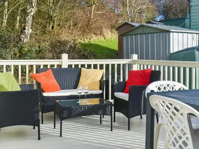a deck with chairs and a table with colorful pillows at Cookies Corner in Millom