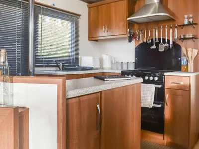a kitchen with wooden cabinets and a black stove top oven at Cookies Corner in Millom