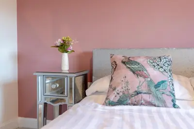 a bed with a pillow and a vase of flowers on a table at Foxglove Haven- 3-Bed Detached - Garden - Drive in Longridge